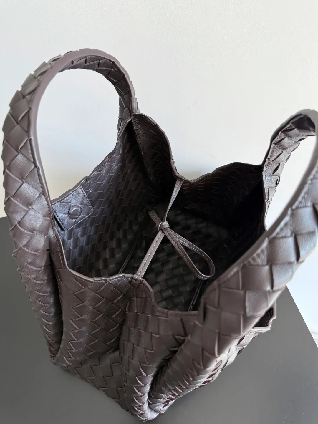Batch 2160 new products are coming! BOTTEGA VENETA Bottega Veneta's 2025 new Campana shoulder bag is on the market~ First of all, I would like to praise the weight of this bag. As a not too small bag, it is very light for daily use. For people like me who need to carry a lot of belongings when going out, this advantage is great, and it greatly reduces the burden of traveling. 🛍️The shape is a bit like a combination of parachute and jodie. The blunt triangle shape is cute and honest. Carrying it on your back when going shopping is a good mood accelerator. The handles and body of the bag are both classic weaves. A tie is added to the original open design. If it is not tied up, the bag will look like a small vegetable basket when carried. Style number: 844249 Size: 33*20*16.5cm